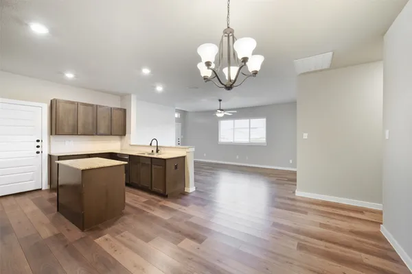 a large kitchen with stainless steel appliances a large counter top a sink and a refrigerator