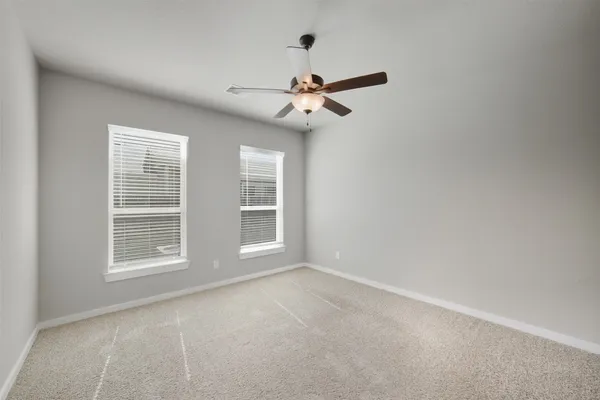 an empty room with windows and ceiling fan