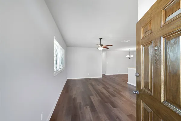 a view of a hallway with wooden floor and a chandelier