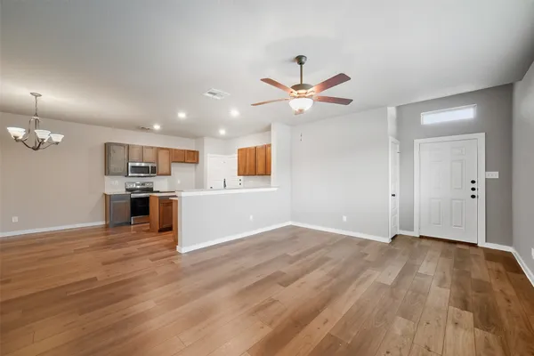an empty room with wooden floor and a kitchen