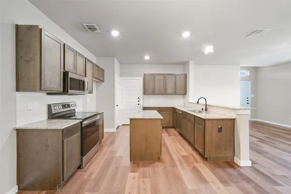 a large kitchen with stainless steel appliances lots of counter space and wooden floor