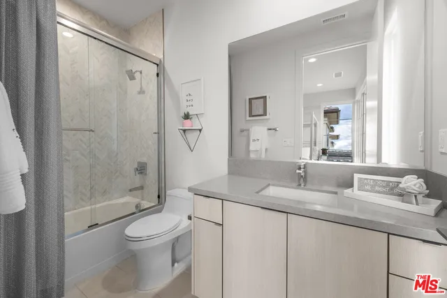 a bathroom with a granite countertop sink a toilet and shower
