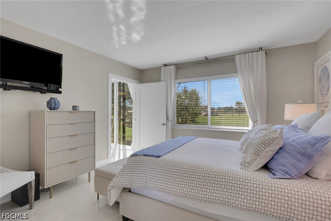 9 High Point Circle North, Unit 101 Naples, FL 34103 - Photo 21 of 49 a bedroom with a bed and a flat tv screen on dresser