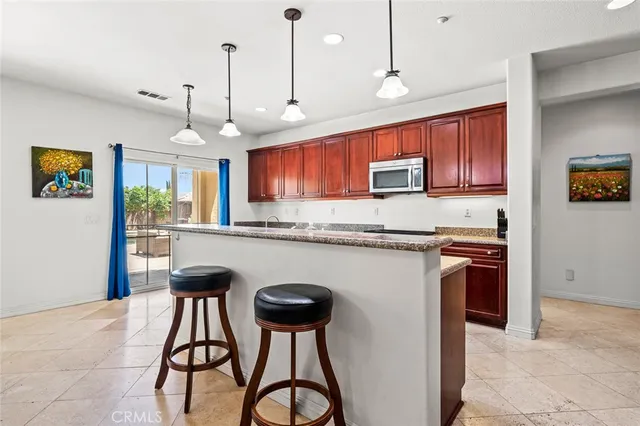 a kitchen with stainless steel appliances granite countertop a stove top oven a sink dishwasher a refrigerator and a microwave