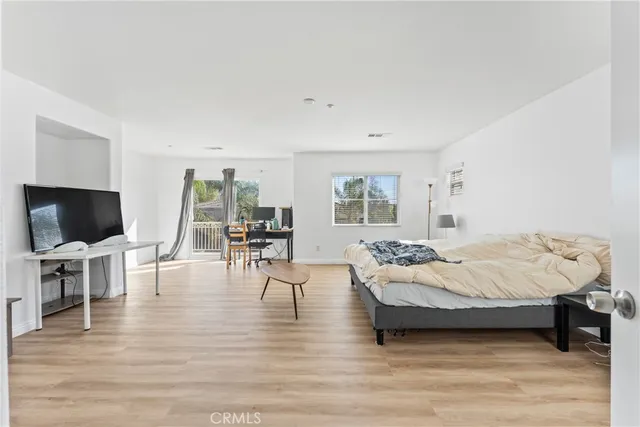 a living room with furniture a flat screen tv and a refrigerator