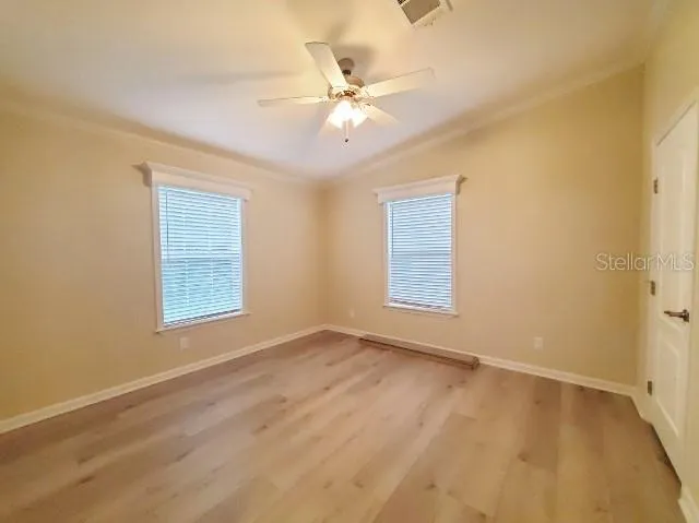 an empty room with wooden floor and fan
