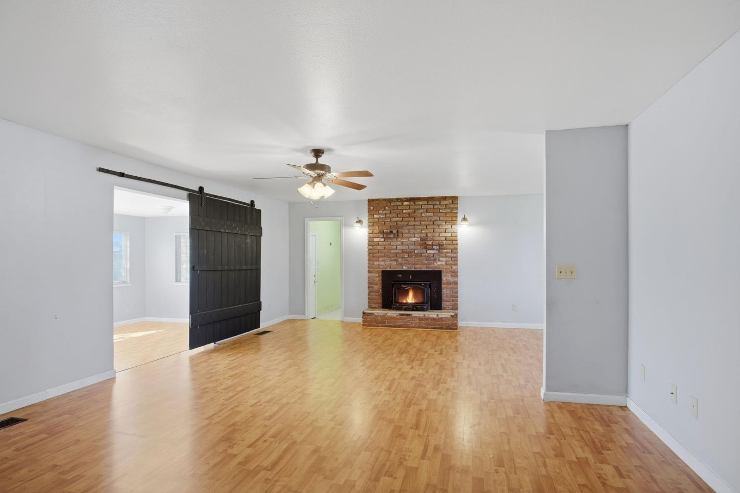 1409 Stonum Road Modesto, CA 95351 - Photo 7 of 40 a view of an empty room with wooden floor a fireplace and a window