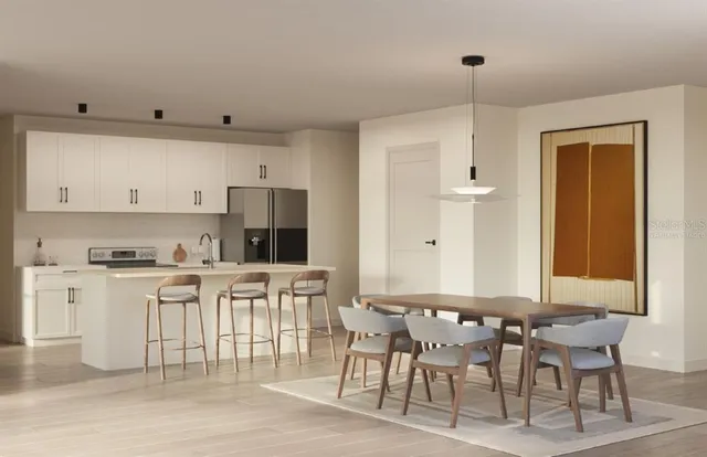 a kitchen with stainless steel appliances granite countertop a stove top oven a sink a dining table and chairs with white cabinets