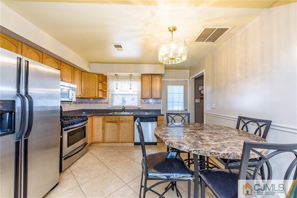 61 Gurley Road Edison, NJ 08817 - Photo 5 of 21 a kitchen with stainless steel appliances granite countertop a kitchen island a stove a table and chairs in it