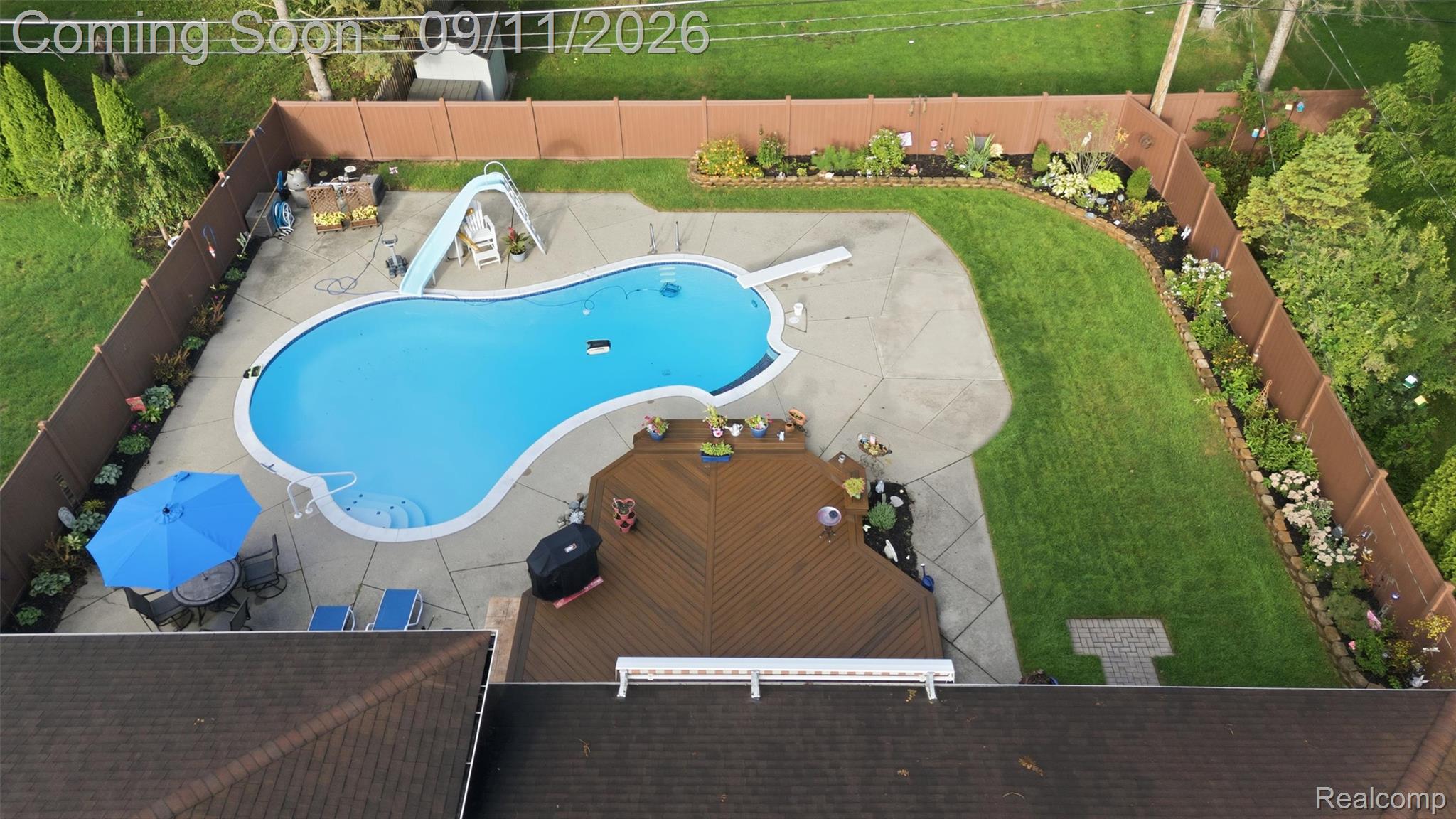 16799 Farmington Road Livonia, MI 48154 - Photo 63 of 71 Freeform swimming pool with a surrounding concrete patio, multi-level wood deck, manicured lawn, and perimeter privacy fencing