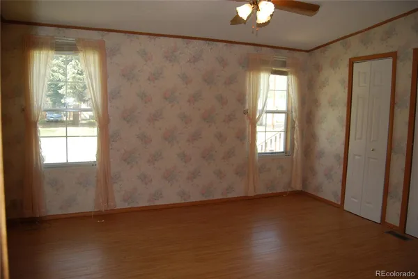an empty room with wooden floor and windows