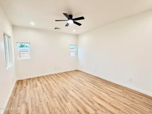 an empty room with wooden floor a ceiling fan and window