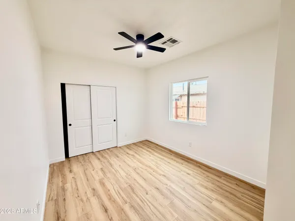 a view of empty room with wooden floor and fan