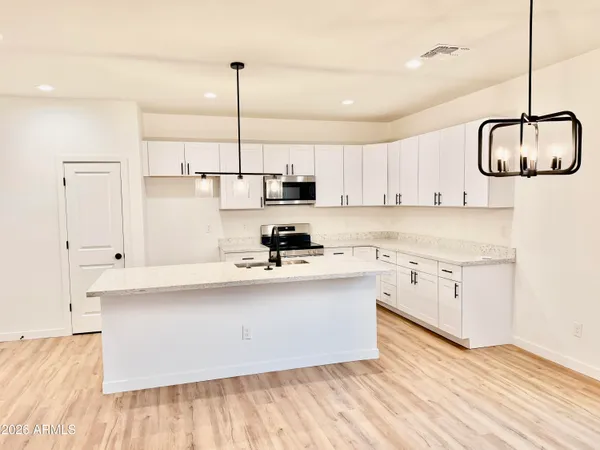 a kitchen with stainless steel appliances granite countertop a sink a stove a refrigerator and white cabinets