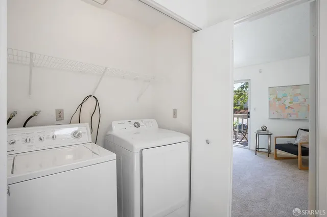 a view of washer and dryer with bathroom in the background