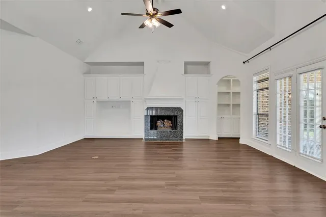 a view of an empty room with a window and wooden floor