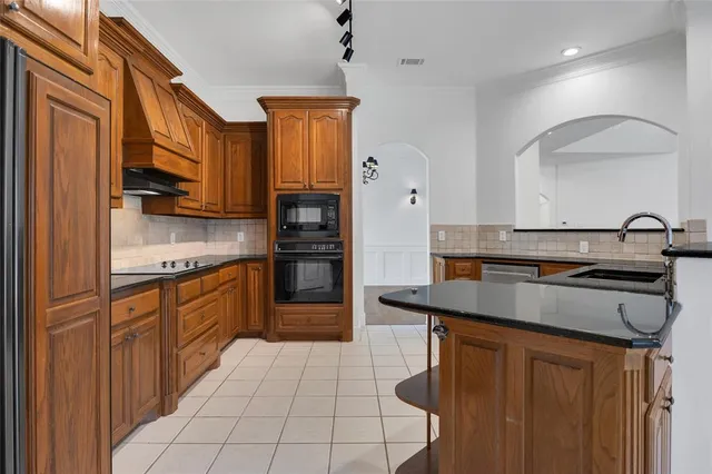 a kitchen with stainless steel appliances granite countertop a sink a stove and a refrigerator