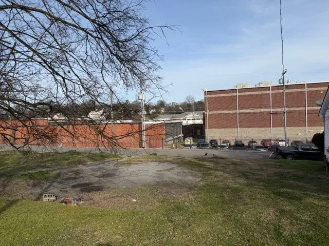 a view of a large white house with a yard and parking space