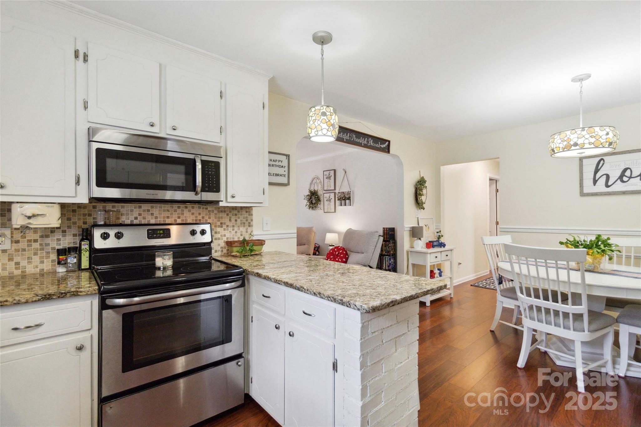1219 Flowe Drive Matthews, NC 28104 - Photo 11 of 30 a kitchen with granite countertop wooden floors and stainless steel appliances