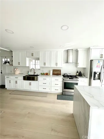 a kitchen with stainless steel appliances kitchen island granite countertop a refrigerator sink and white cabinets