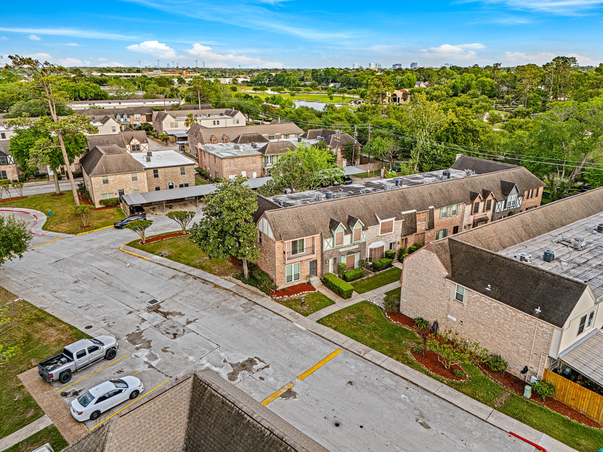 830 Threadneedle Street, Unit 240 Houston, TX 77079 - Photo 33 of 33 This aerial photo showcases a quiet residential neighborhood featuring rows of townhouses with brick exteriors and well-maintained landscaping. The area is surrounded by lush greenery and offers a peaceful suburban atmosphere, with nearby roads and parking spaces for convenience.