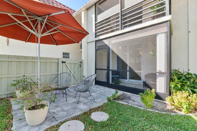 a view of a chair and table of backyard with potted plants