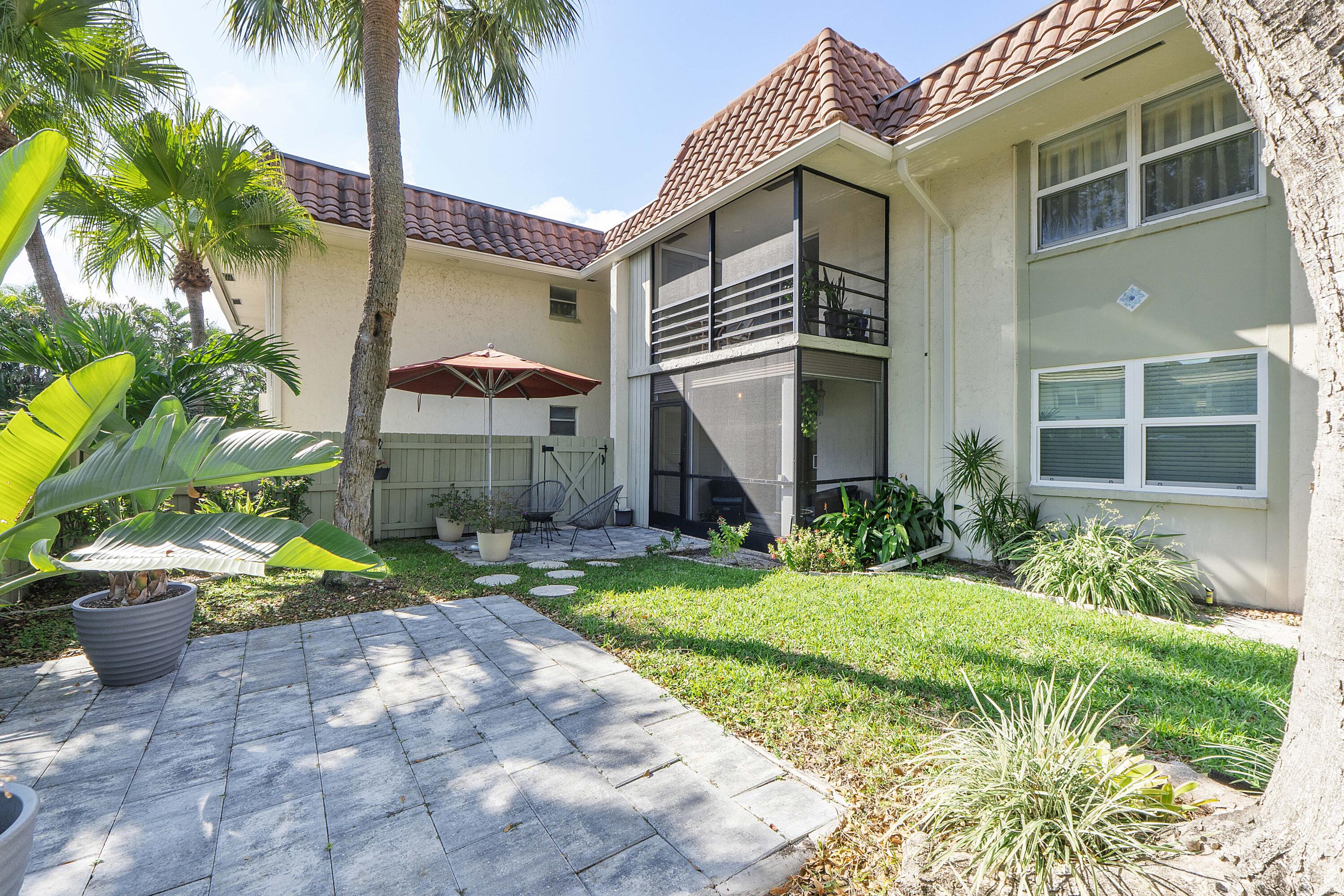 1100 Northwest 13th Street, Unit 192D Boca Raton, FL 33486 - Photo 27 of 42 a front view of a house with a yard and potted plants