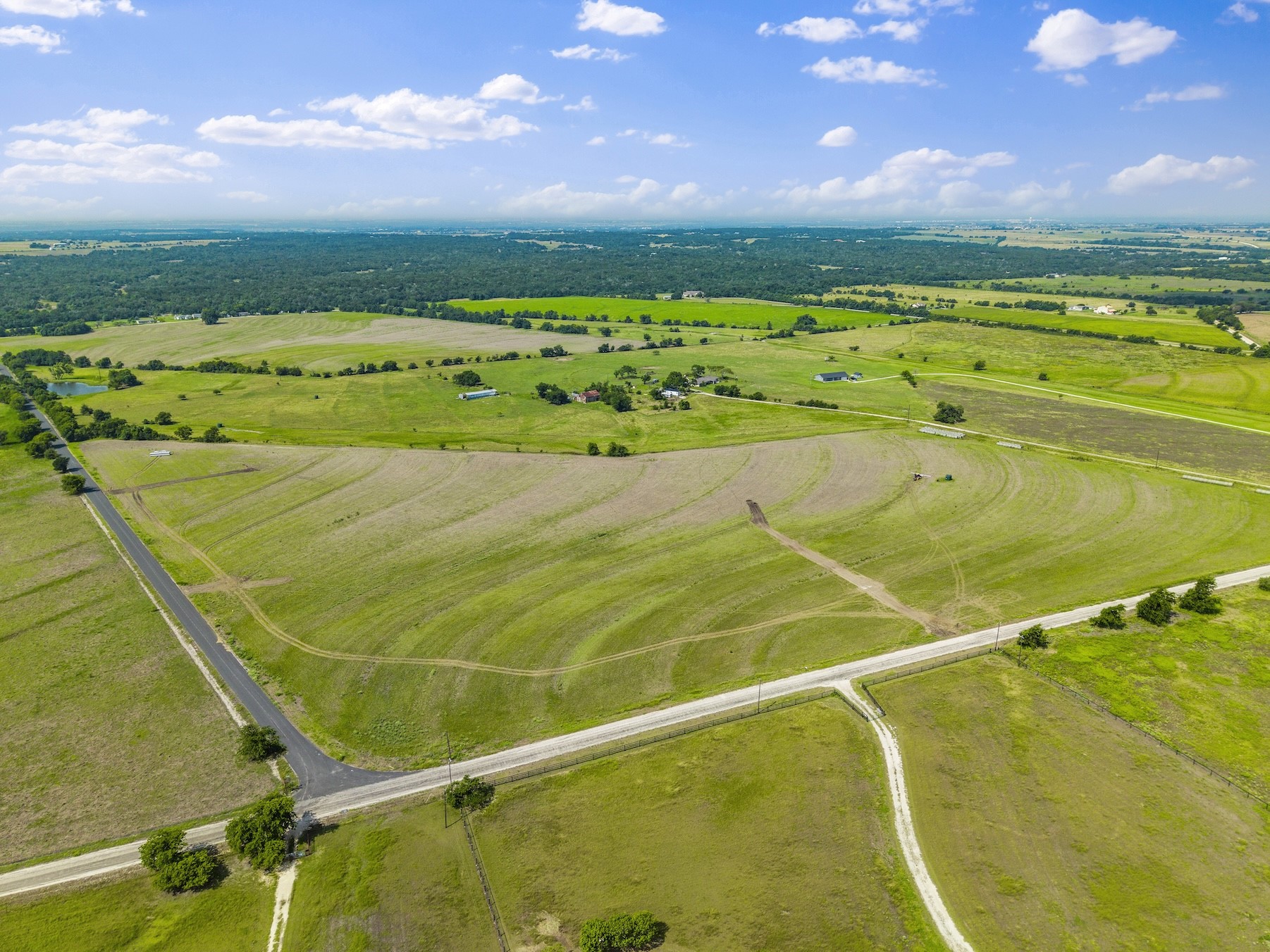 1 County Road 327 Road Granger, TX 76530 - Photo 4 of 27 Vast rolling pastures and mature trees stretch across this expansive countryside acreage under bright blue skies.
