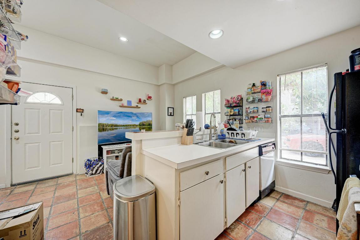 712 Graham Place, Unit 101 Austin, TX 78705 - Photo 12 of 19 Kitchen with a peninsula, light countertops, white cabinetry, freestanding refrigerator, and healthy amount of natural light