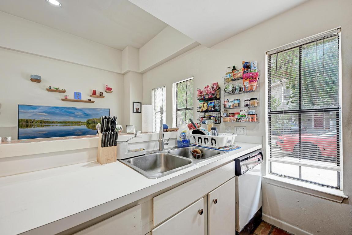 712 Graham Place, Unit 101 Austin, TX 78705 - Photo 14 of 19 Kitchen with open shelves, light countertops, white cabinetry, and white dishwasher