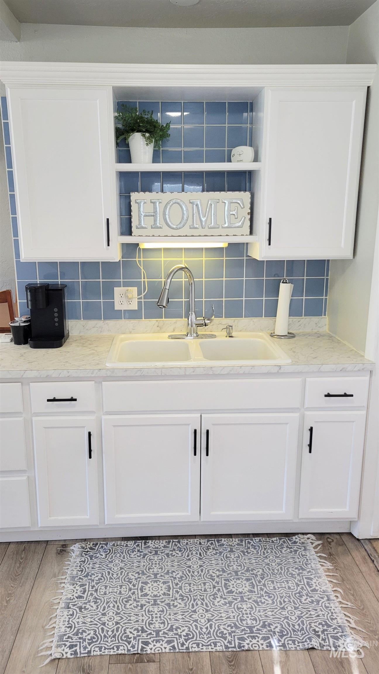 814 Baker Street Boise, ID 83706 - Photo 18 of 26 Kitchen sink area featuring white shaker-style cabinetry, a double basin sink, light-colored countertops, and a blue square tile backsplash