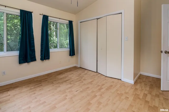 a view of a wooden house with a small yard plants and large trees