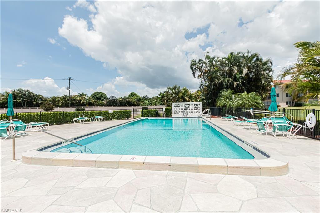 1 High Point Circle West, Unit 102 Naples, FL 34103 - Photo 27 of 35 a view of a swimming pool with a lounge chair