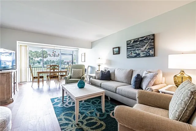 a living room with furniture wooden floor and a large window
