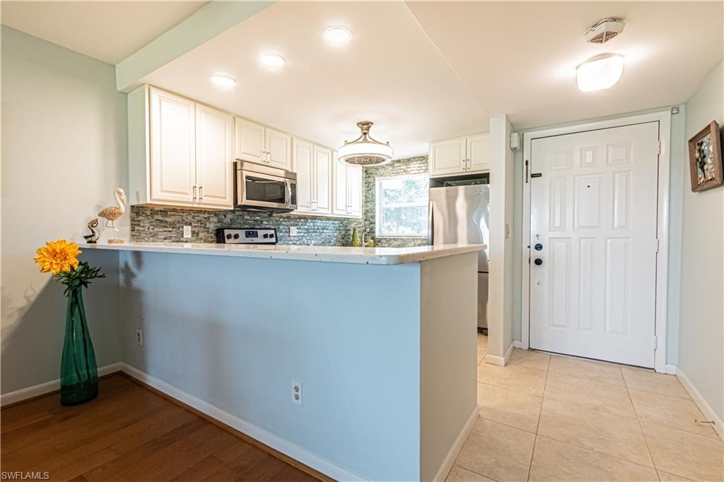 1 High Point Circle West, Unit 102 Naples, FL 34103 - Photo 5 of 35 a kitchen with kitchen island a sink a stove a refrigerator and cabinets