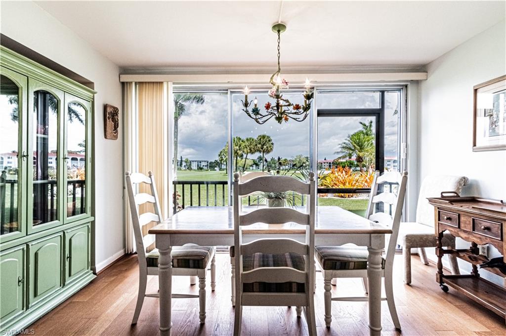 1 High Point Circle West, Unit 102 Naples, FL 34103 - Photo 8 of 35 a dining room with furniture a chandelier and wooden floor
