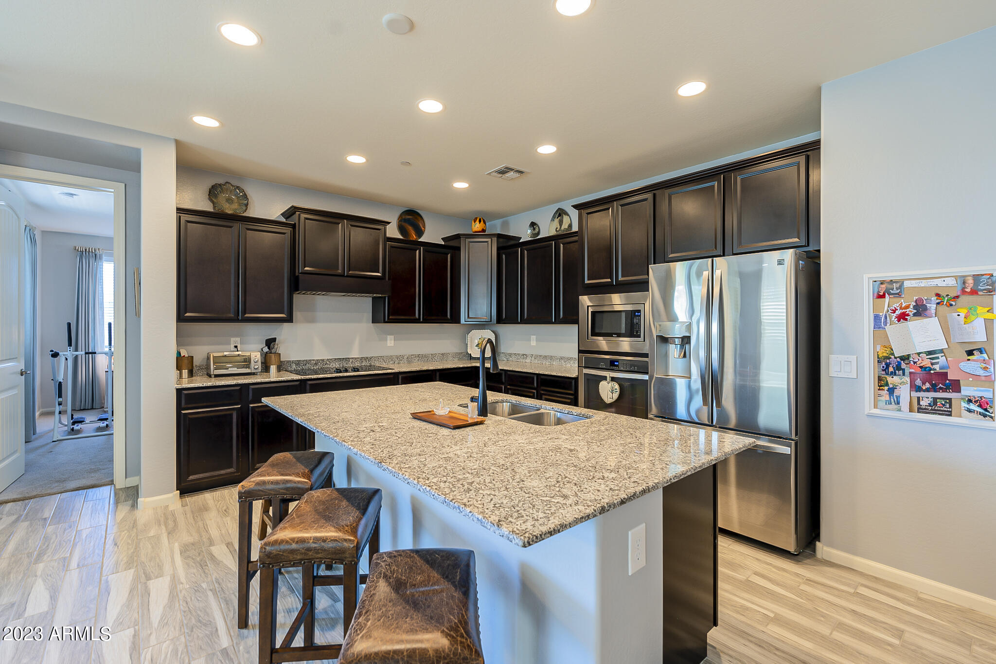 13719 West Linanthus Road Peoria, AZ 85383 - Photo 3 of 38 a kitchen with stainless steel appliances kitchen island granite countertop a table chairs microwave and refrigerator