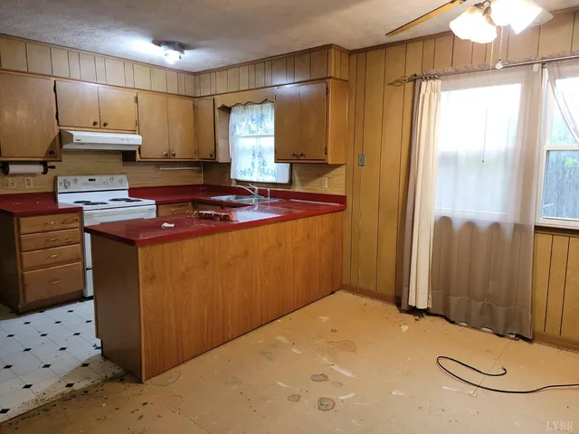 a kitchen with stainless steel appliances a stove a refrigerator a sink with white cabinets and wooden floor