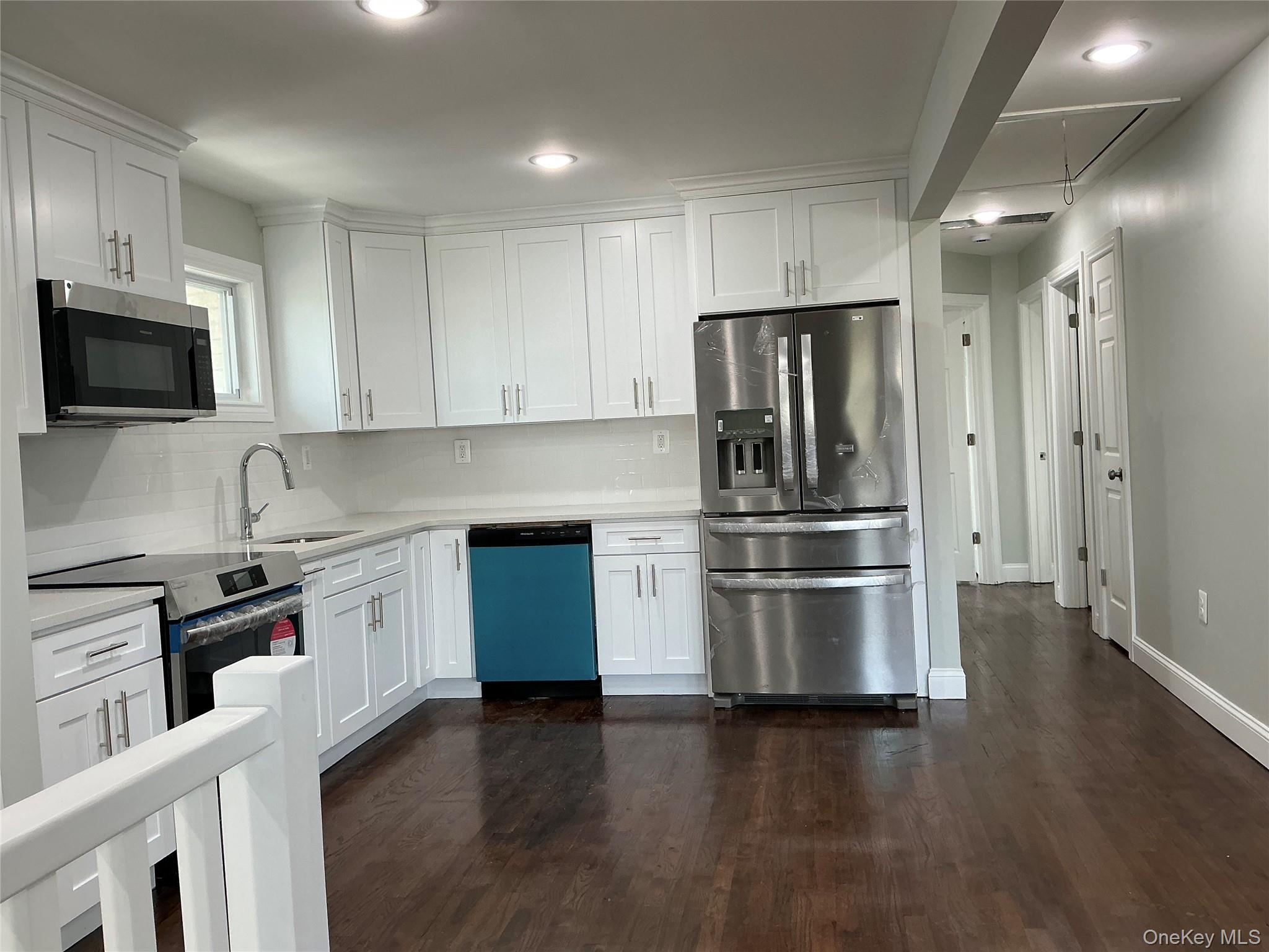 248 East Shore Road Lindenhurst, NY 11757 - Photo 17 of 46 Kitchen featuring appliances with stainless steel finishes, dark wood-type flooring, white cabinetry, tasteful backsplash, and recessed lighting
