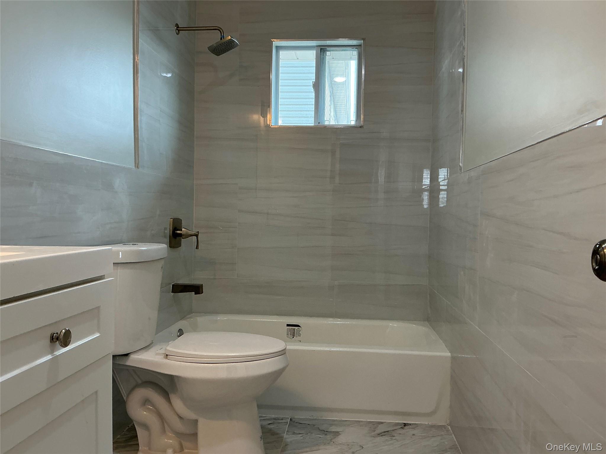 248 East Shore Road Lindenhurst, NY 11757 - Photo 25 of 46 Full bathroom with tile walls, bathtub / shower combination, vanity, and marble look tiles