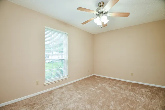 an empty room with windows and fan