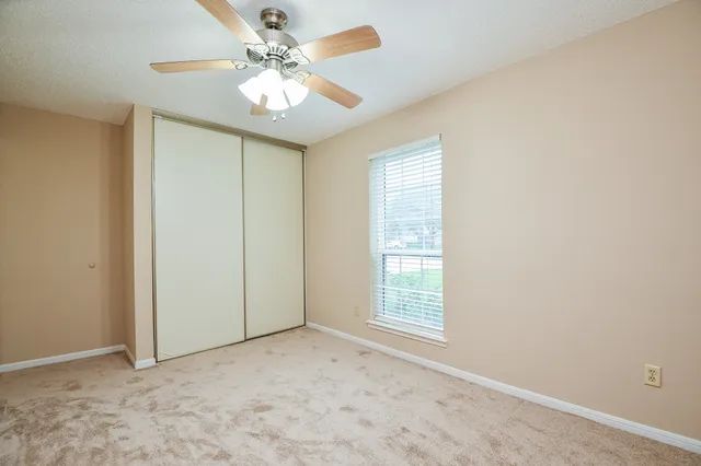 an empty room with windows and ceiling fan