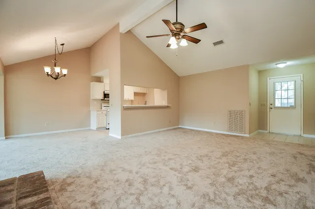 an empty room with chandelier fan and windows