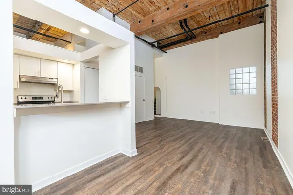 a view of a refrigerator in kitchen and an empty room