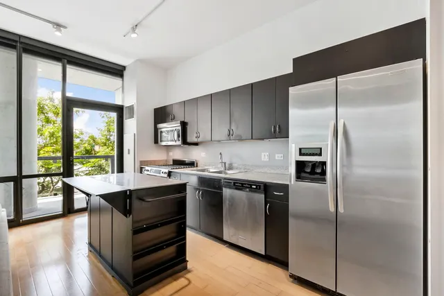 a kitchen with kitchen island a counter top space a sink stainless steel appliances and cabinets