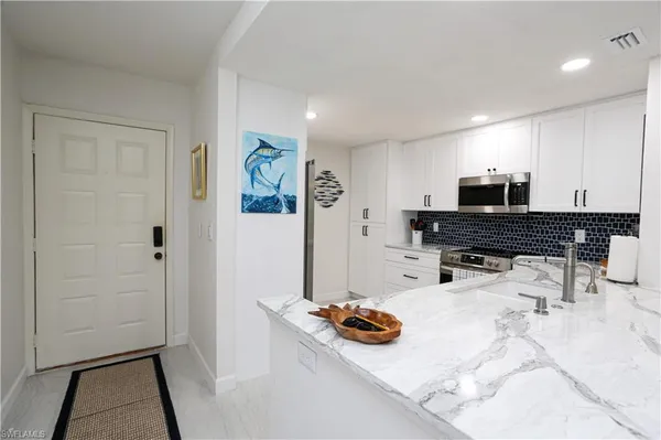 a kitchen with stainless steel appliances granite countertop a stove a refrigerator a sink a dining table and chairs with wooden floor