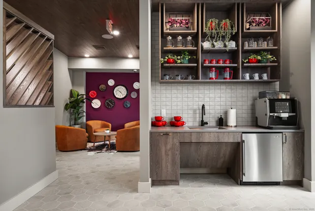 a room with lots of white furniture and a book shelf
