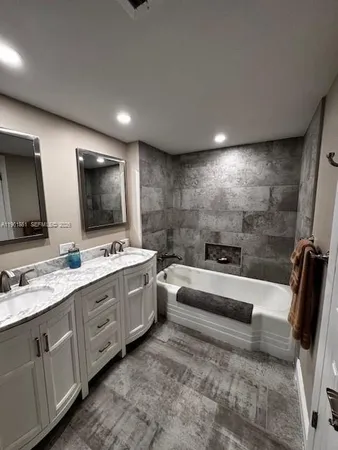 a large white bathroom with a double vanity sink a mirror and a bathtub