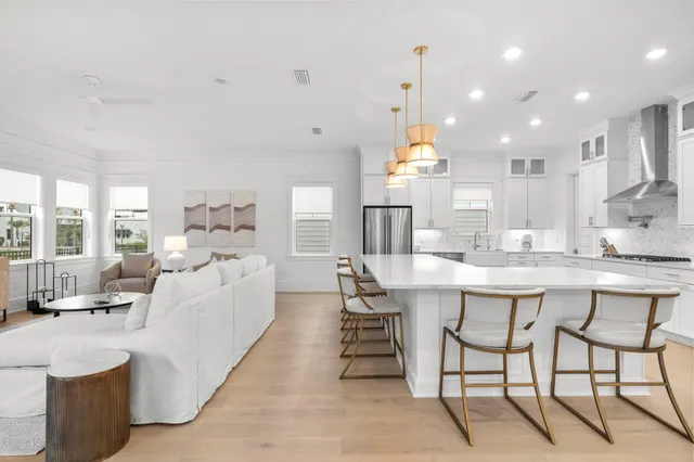 a large white kitchen with a large island oven a sink and a large window