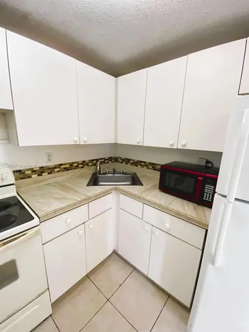 a kitchen with granite countertop white cabinets and white appliances